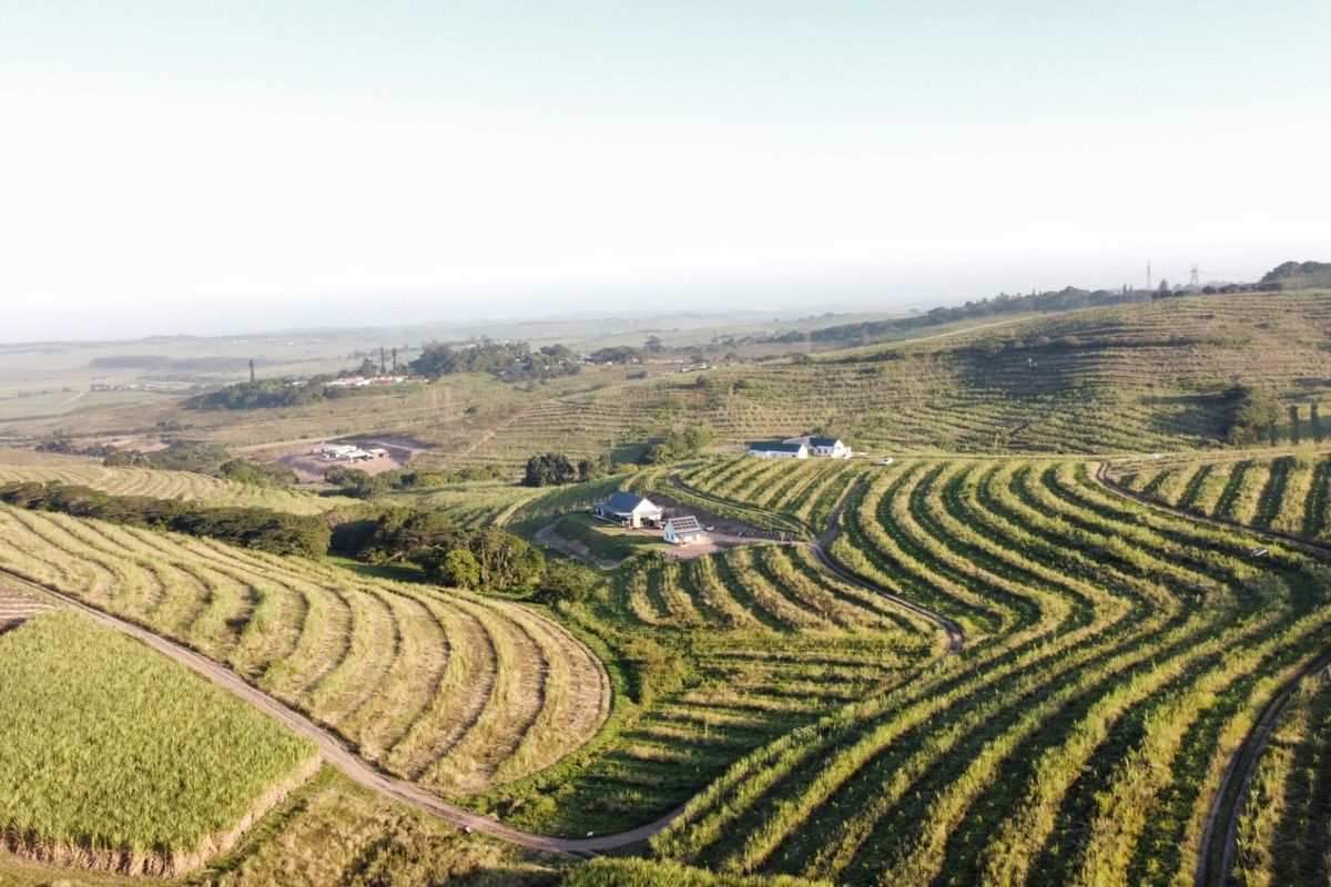 An aerial view of a large small holding property featuring extensive agricultural fields, access roads, and residential buildings with solar installations.
