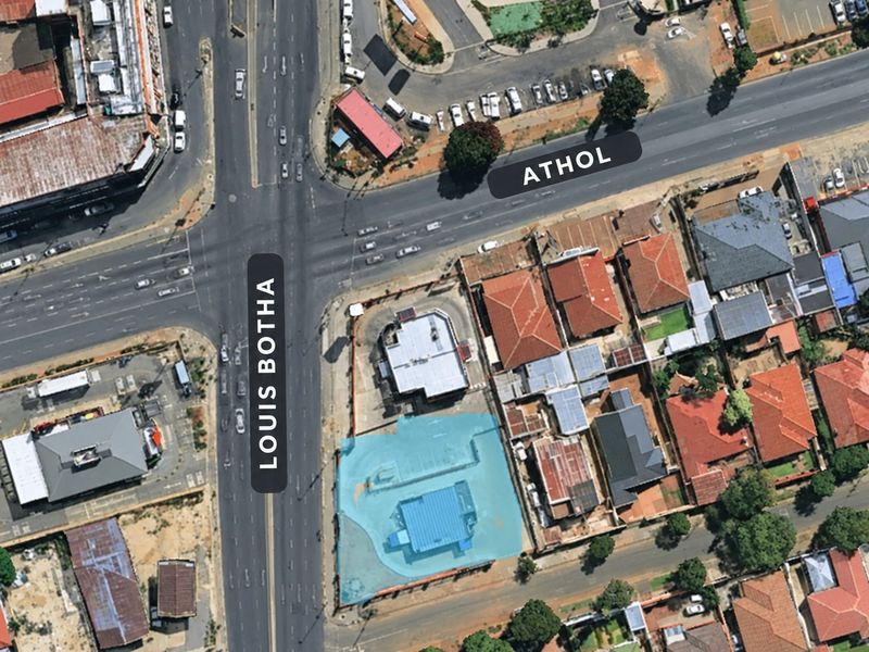 Aerial view of a commercial property located at a major intersection, featuring building structures and paved parking areas.