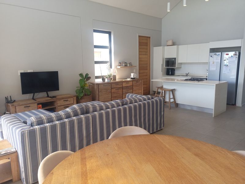 Spacious open-plan living area featuring a modern kitchen with island, gas hob, and tiled flooring under a high vaulted ceiling.