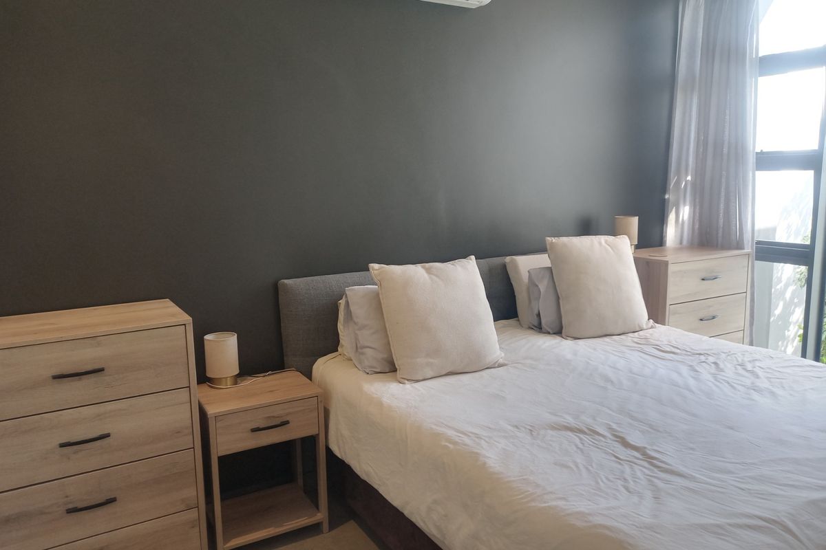 A well-maintained bedroom featuring a dark accent wall, split-system air conditioning, and large windows allowing for natural light.