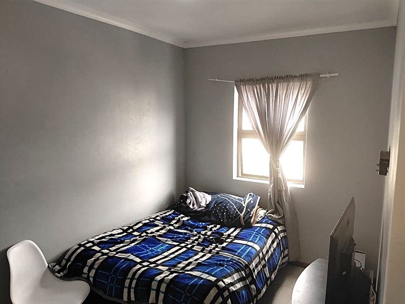 A compact bedroom featuring neutral grey walls and a single window, providing a functional space for rest.