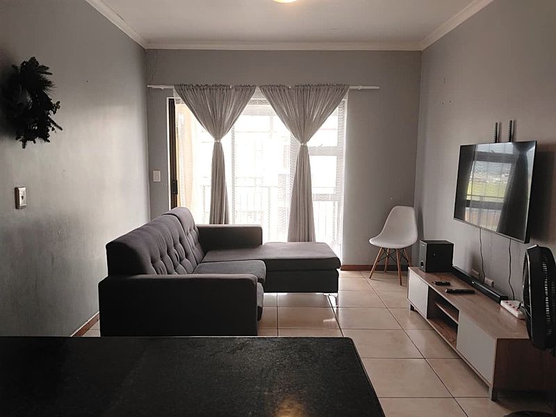 A living room featuring tiled flooring and a sliding glass door leading to a balcony, providing natural light and access to outdoor space.