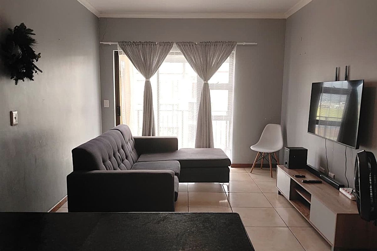 A living room featuring tiled flooring and a sliding glass door leading to a balcony, providing natural light and access to outdoor space.