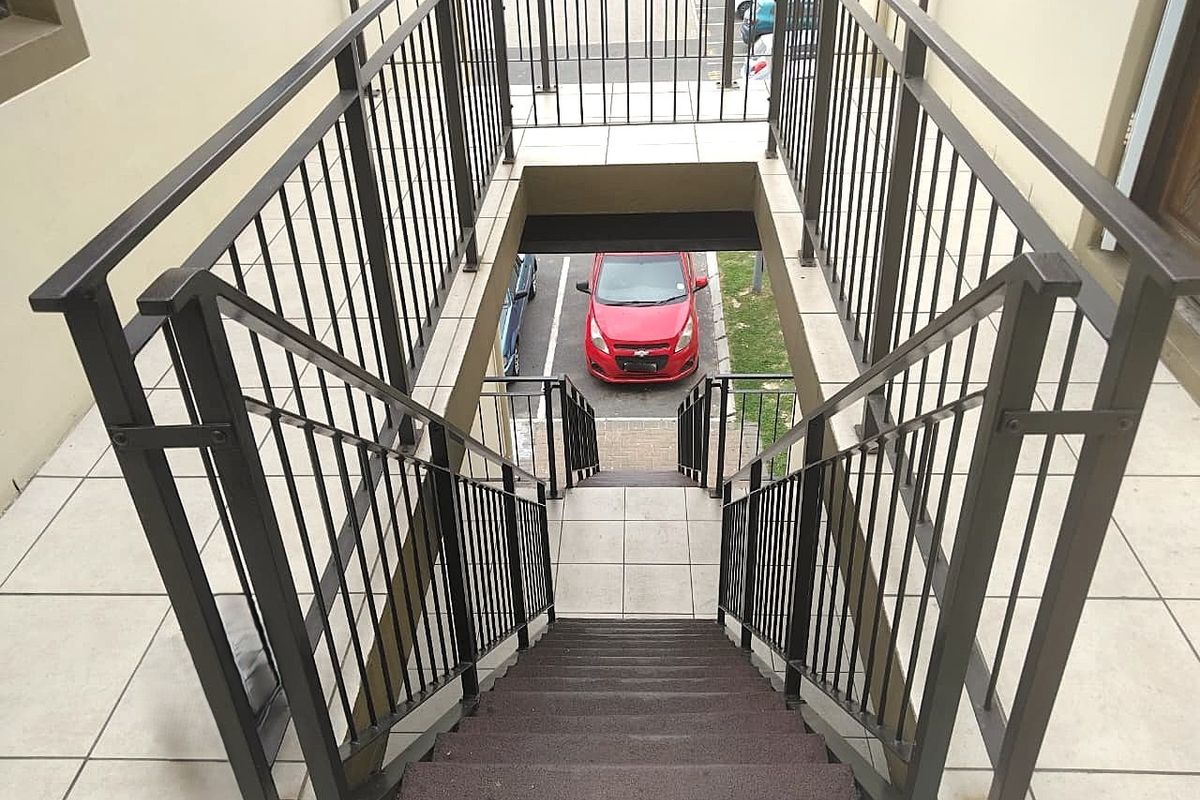An exterior staircase with metal balustrades and tiled landings providing access to the apartment level.