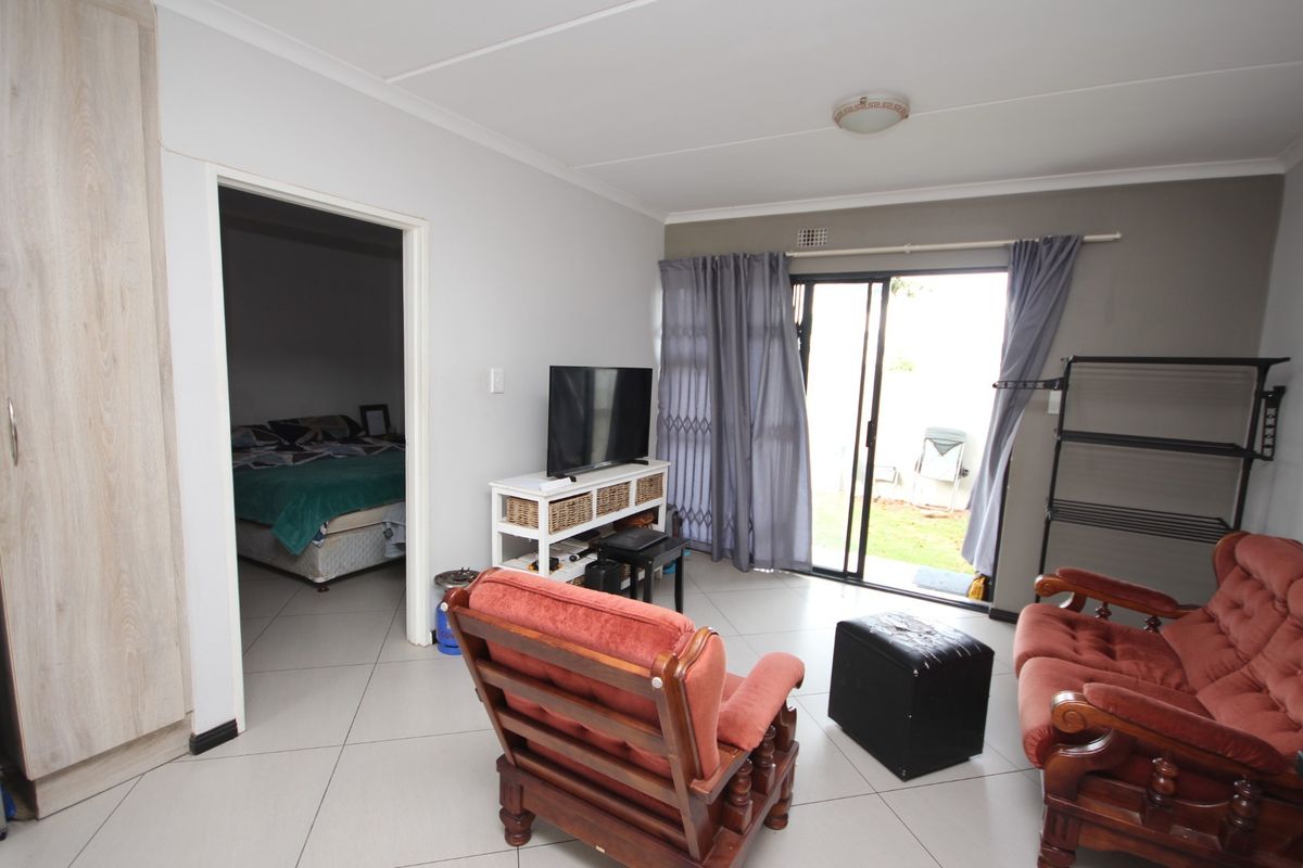 A living room featuring tiled flooring, a built-in cupboard, and a sliding glass door providing access to the outdoor area.