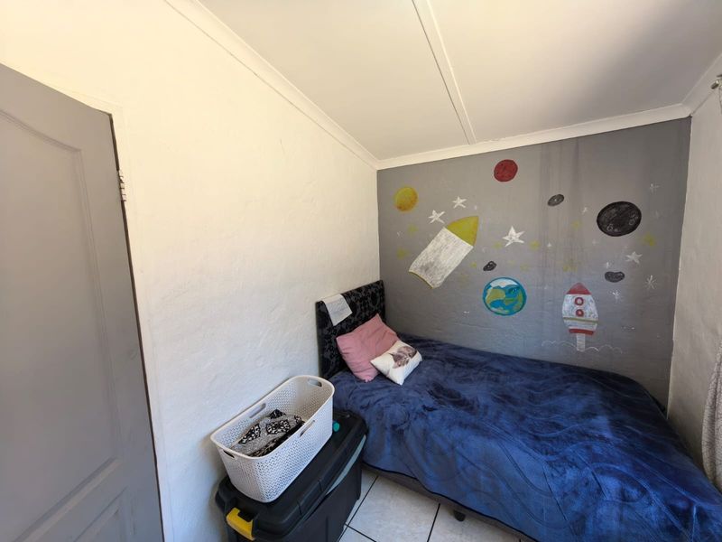 A compact bedroom featuring tiled flooring and a decorative mural on the feature wall.
