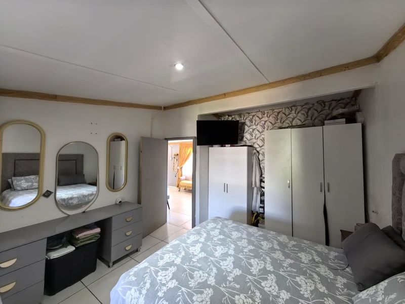 A bedroom featuring built-in cupboards, tiled flooring, and decorative wall accents, requiring minor cosmetic updates to improve the overall finish.