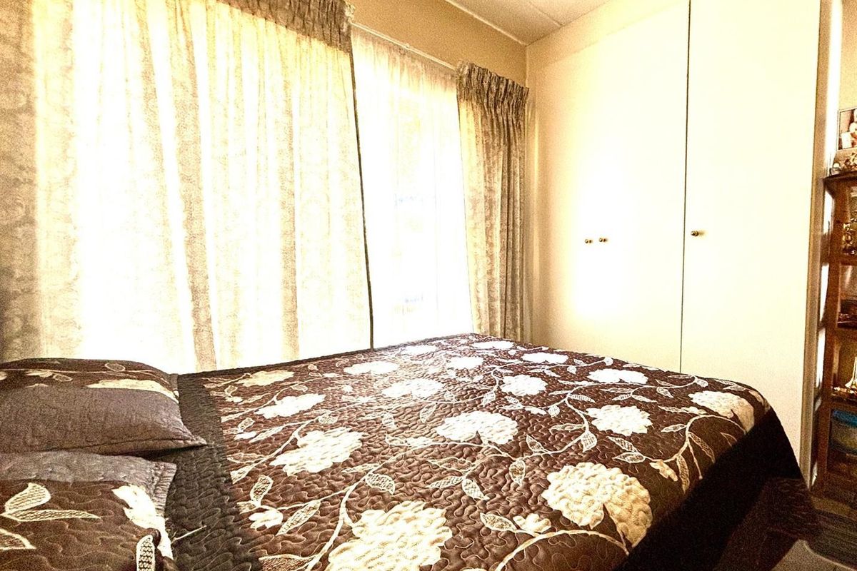 A bedroom featuring built-in cupboards and natural light through window curtains.