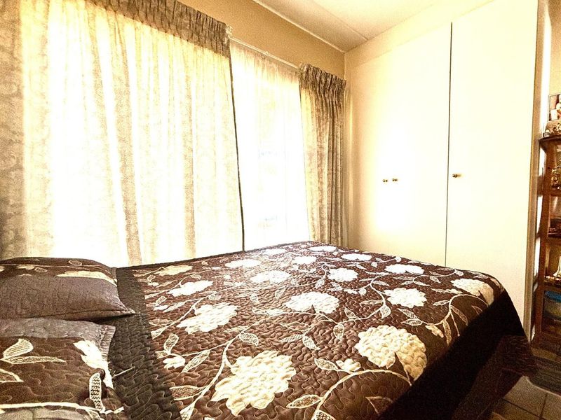A bedroom featuring built-in cupboards and natural light through window curtains.