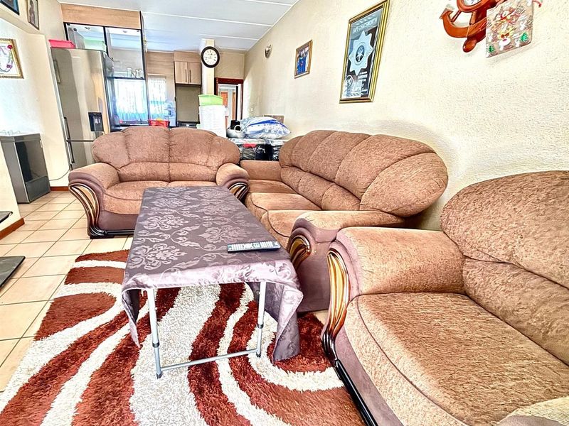 An open-plan living area featuring tiled flooring and a connected kitchen space, offering a functional layout for daily living.