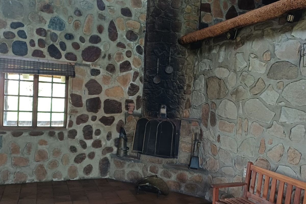 Rustic living room featuring extensive natural stone wall cladding, a large stone fireplace with hearth, and traditional tiled flooring.