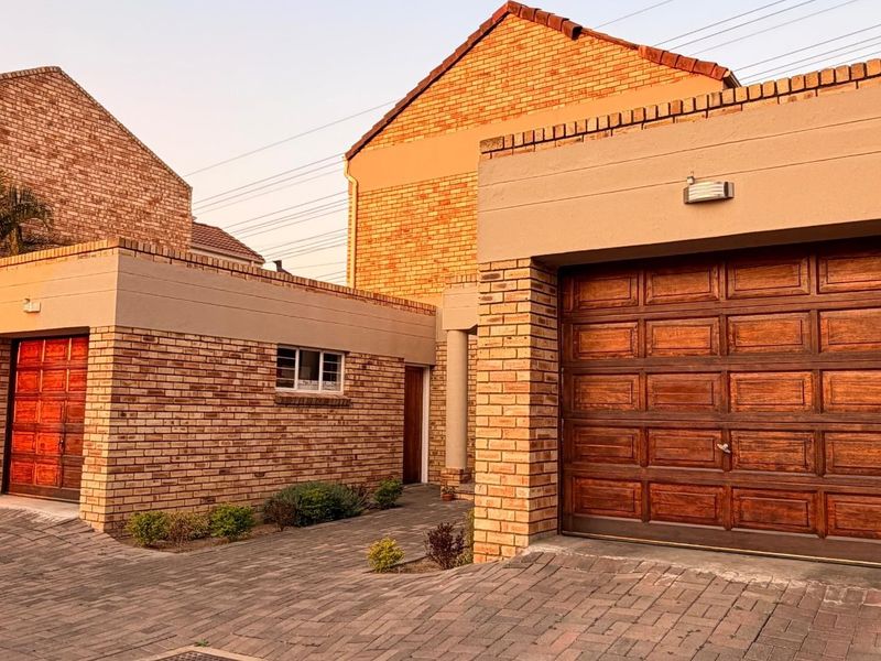 Front exterior view of a face brick residential property featuring a double garage, a single garage, and a paved driveway.