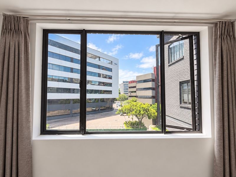 A clear view of the surrounding urban landscape and office buildings framed by a modern black-framed casement window.