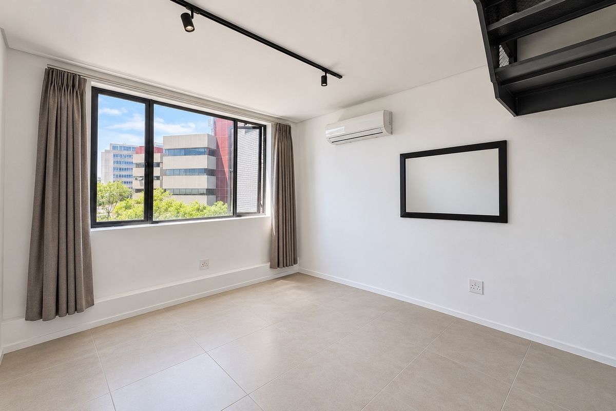 A bright, modern living area featuring tiled floors, track lighting, a split-system air conditioner, and large windows with urban views.