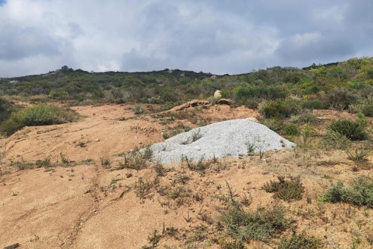 A view of a vacant residential plot featuring natural terrain and a paved verge, ready for development.