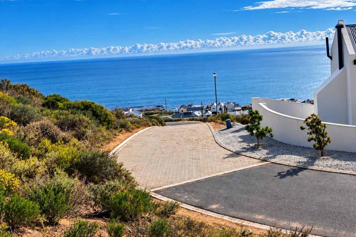 A scenic view overlooking the coastline and ocean, featuring a paved driveway and modern retaining wall structure.