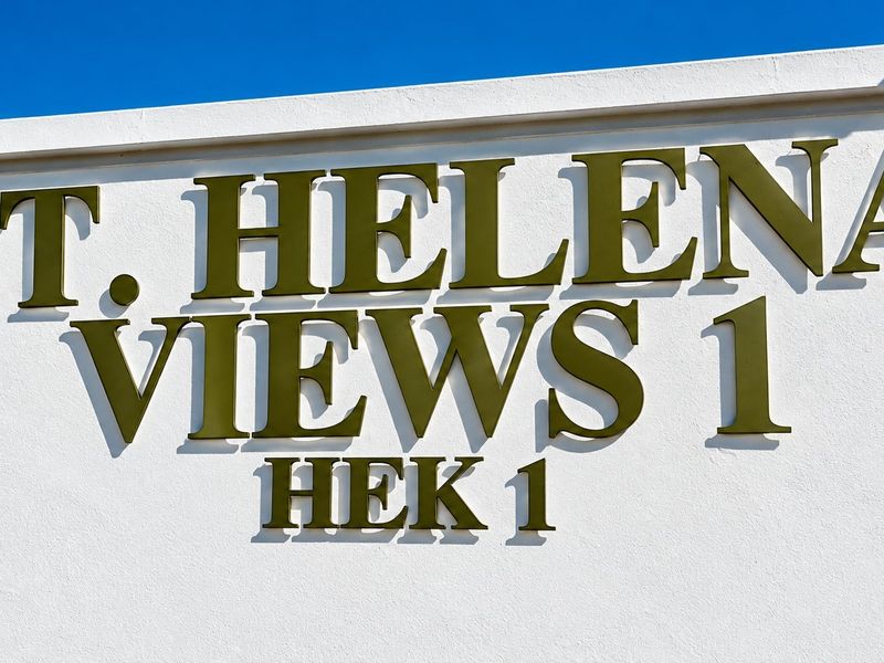 A clear view of the St. Helena Views 1 estate signage mounted on a clean, white exterior wall.