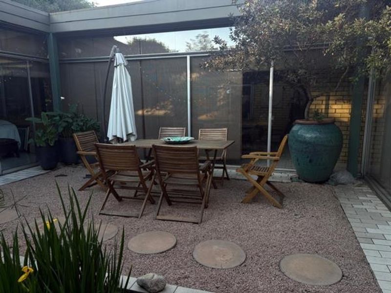 A private outdoor patio area featuring gravel ground cover, a paved walkway, and large sliding glass doors providing seamless access to the interior living space.