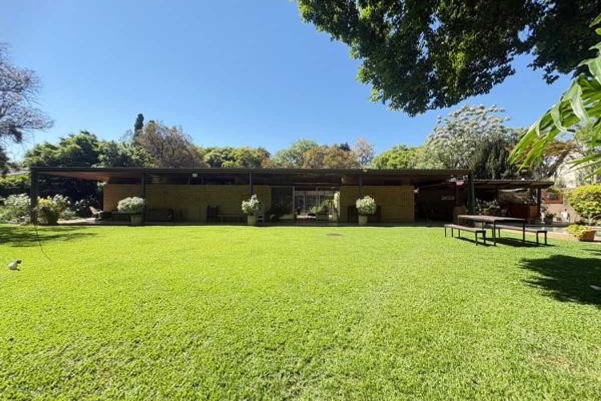 Spacious rear garden featuring a large manicured lawn and a covered patio area, providing an ideal space for outdoor relaxation and entertainment.