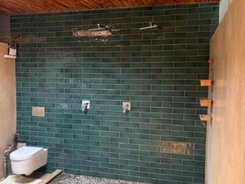 Modern bathroom featuring a walk-in shower with pebble flooring, green subway tile walls, and a warm timber ceiling.