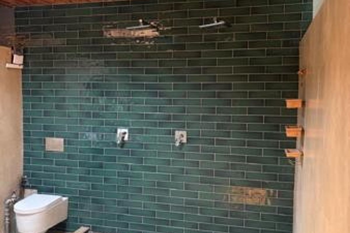 Modern bathroom featuring a walk-in shower with pebble flooring, green subway tile walls, and a warm timber ceiling.