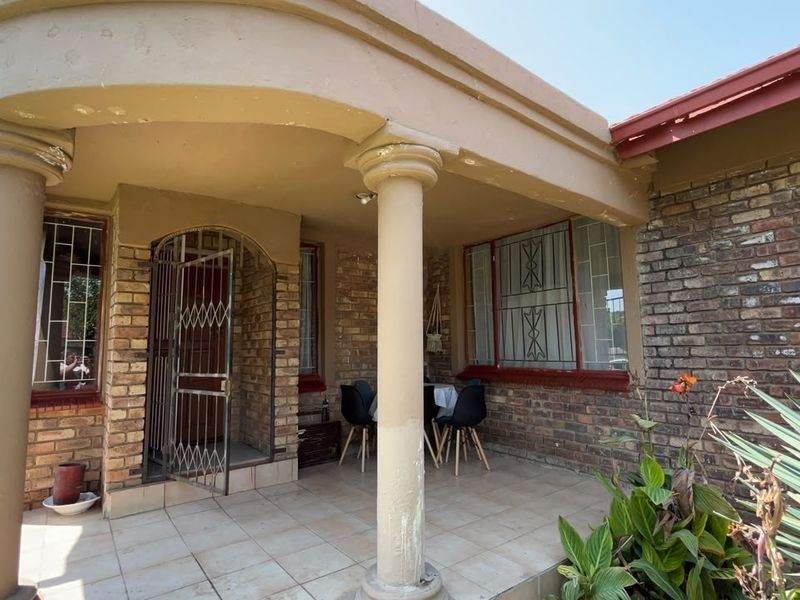 Covered patio area featuring brick masonry, tiled flooring, and structural columns, providing a functional outdoor space for relaxation.