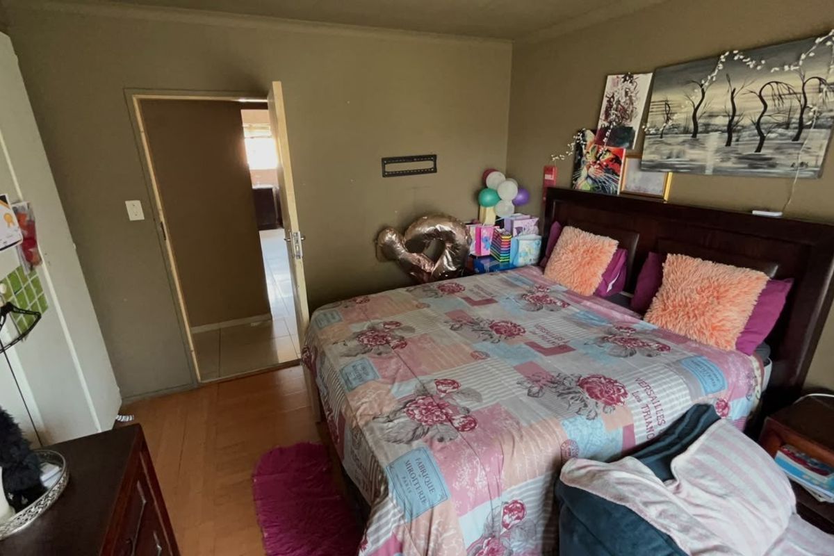 A bedroom featuring laminate flooring and a built-in cupboard, currently showing signs of wear on the wall surfaces.