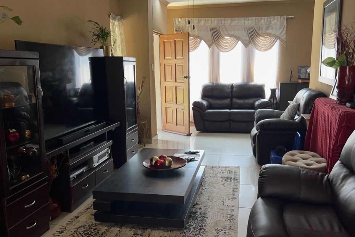 A comfortable living room featuring tiled flooring and direct access to the exterior through a timber door.