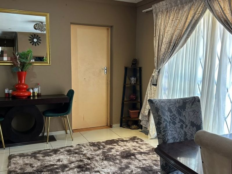 A living area featuring tiled flooring and a window fitted with a security gate, offering a functional space with neutral wall tones.