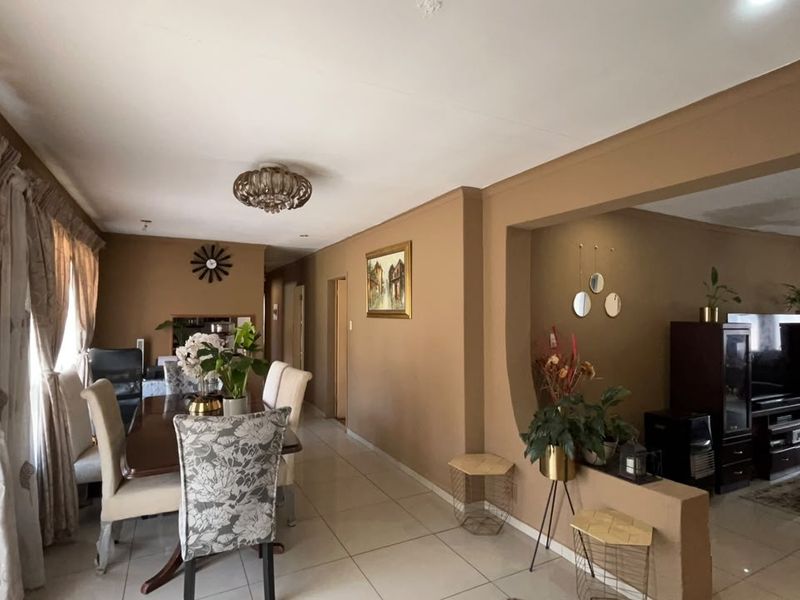 Open-plan living and dining area featuring tiled flooring, a decorative archway, and a built-in partition wall, creating a connected and functional living space.