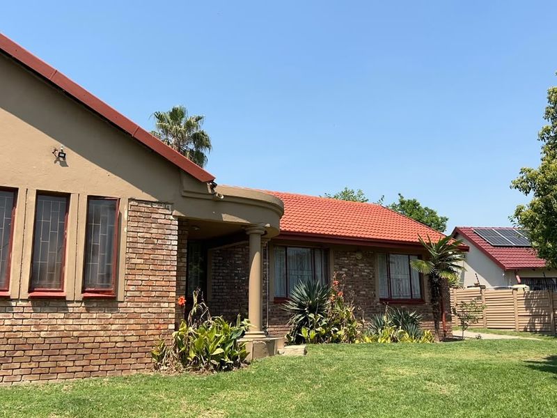 Front view of a single-story brick house featuring a tiled roof, covered porch with a decorative column, and a well-maintained front lawn.