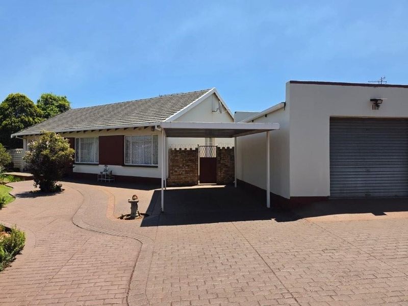 Front exterior view of a single-story house featuring a paved driveway, attached carport, and a secure garage.