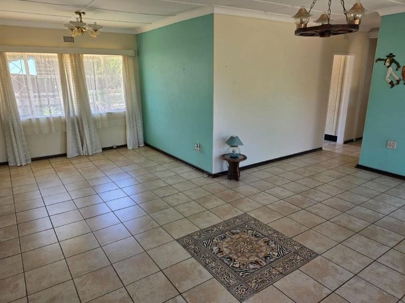 Spacious living area featuring tiled flooring with a decorative inlay, neutral and teal wall finishes, and ceiling lighting fixtures.