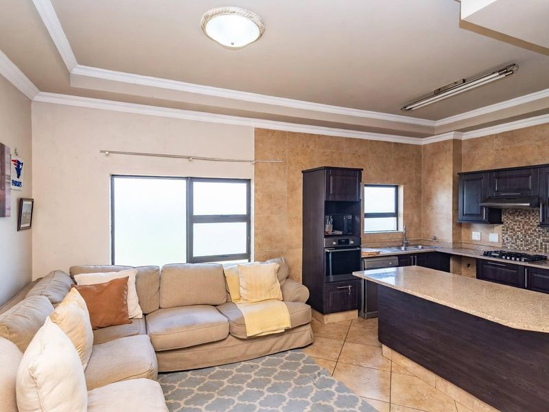 Open-plan living area featuring a modern kitchen with dark wood cabinetry, granite countertops, built-in oven, and gas hob, seamlessly connected to the lounge space.