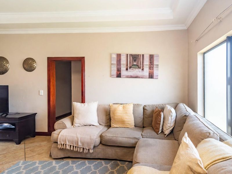 A comfortable living room featuring tiled flooring, crown molding, and a large window, providing a neutral base for interior design updates.