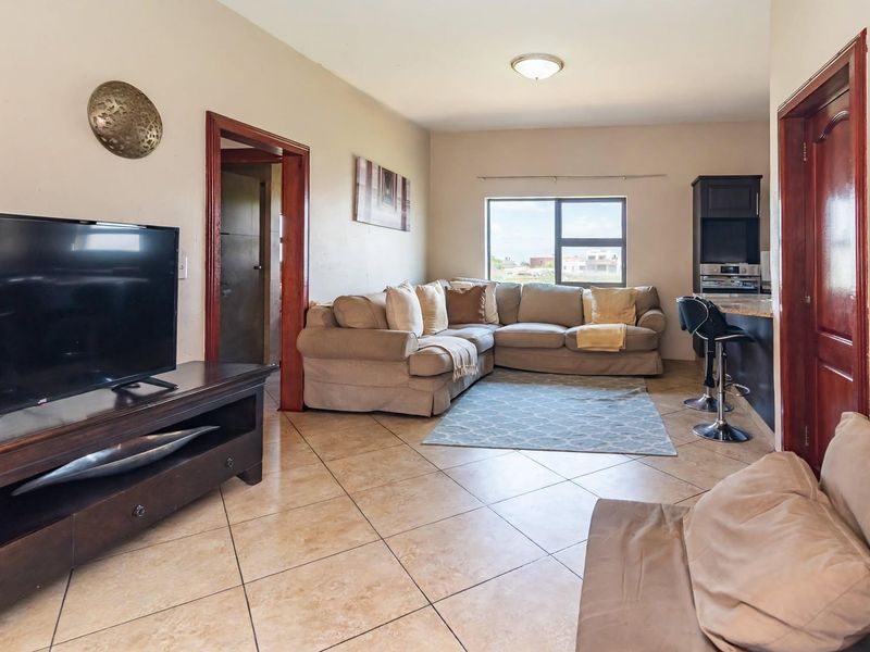 Open-plan living area featuring tiled flooring, integrated kitchen cabinetry with granite countertops, and direct access to adjacent rooms through timber-framed doorways.