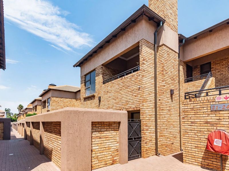 Exterior view of a multi-story face brick residential complex featuring paved walkways, balconies, and integrated fire safety equipment.