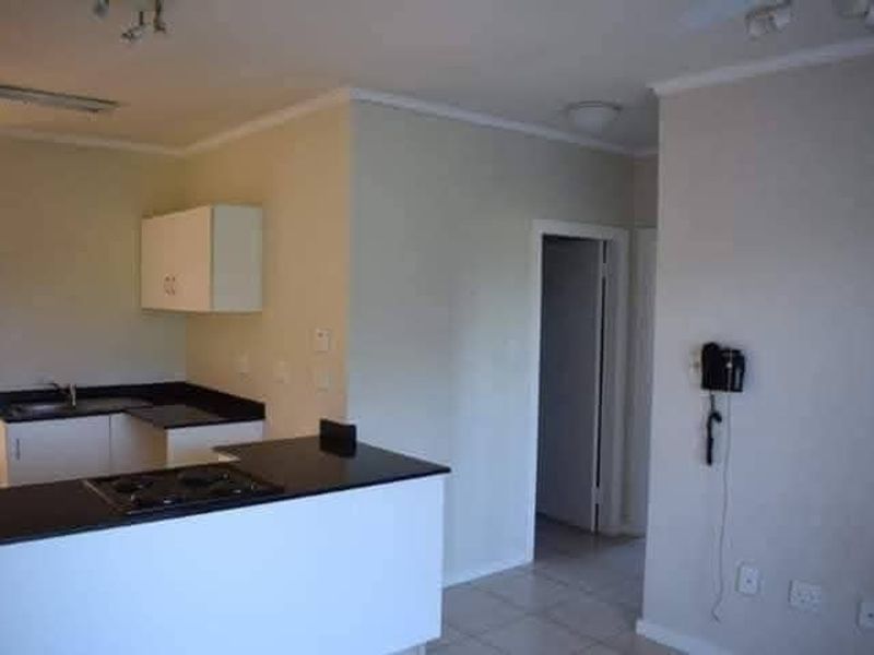 Open plan living area featuring a functional kitchen with black granite countertops, built-in hob, and tiled flooring throughout.