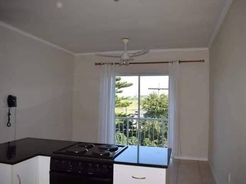 Open plan living area featuring a kitchen with black granite countertops, built-in stove, and a sliding door leading to a balcony.