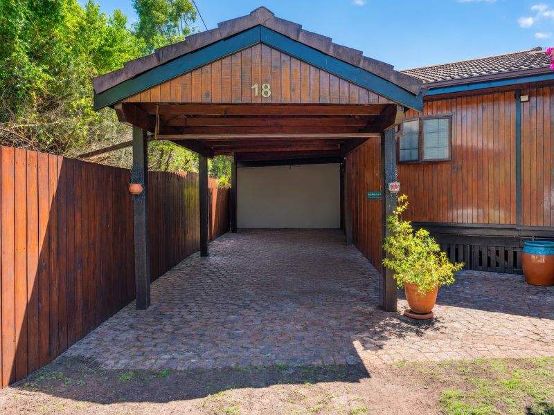 A well-maintained timber carport with a cobblestone driveway, providing covered parking space for the property.