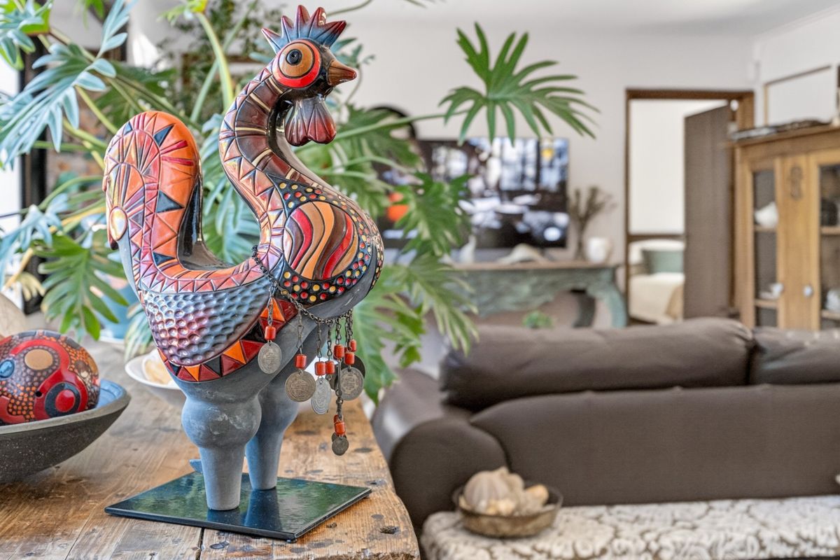 A view of a living room interior featuring a decorative rooster sculpture in the foreground with a blurred living area in the background.