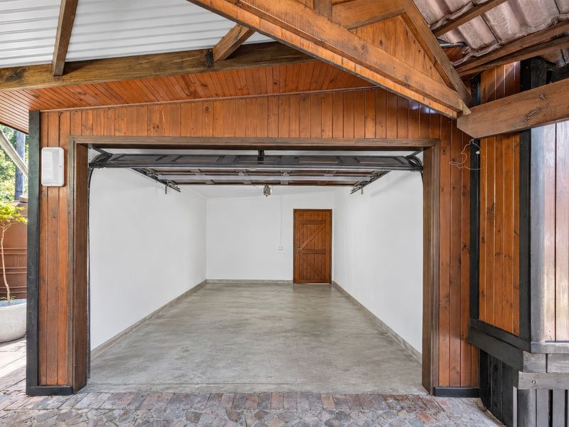 A clean, empty garage featuring timber-clad walls and ceiling, concrete flooring, and a secure sectional door, providing ample space for vehicle storage.