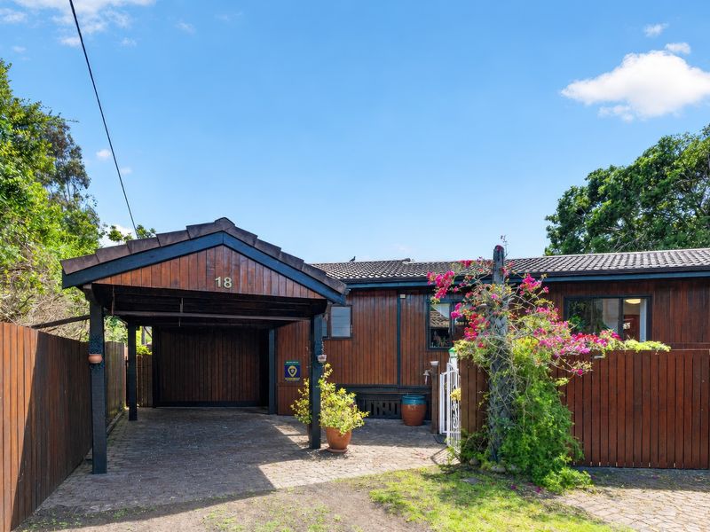 Front exterior view of the property featuring a timber carport, paved driveway, and timber cladding facade.