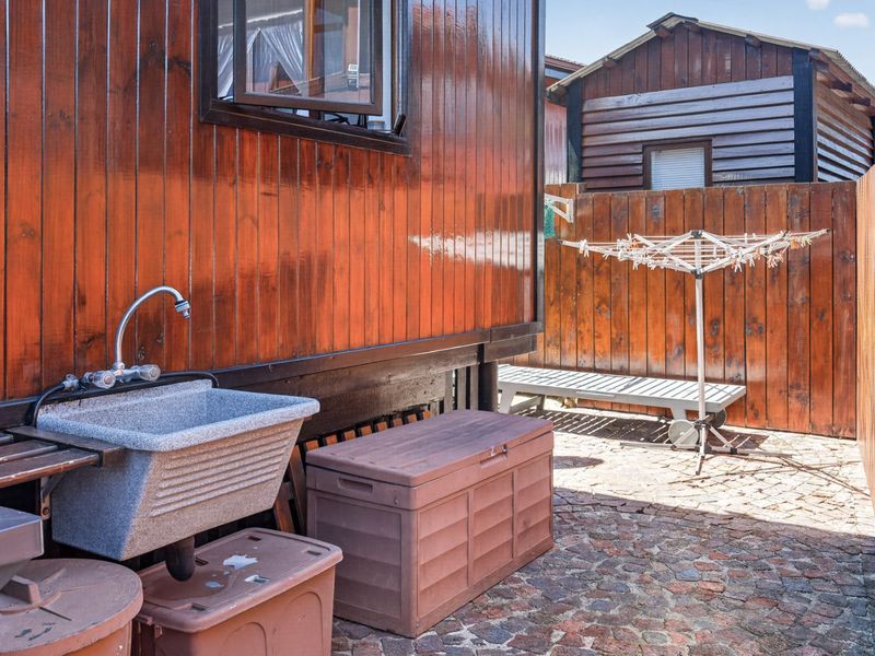 A functional rear courtyard area featuring timber wall cladding, a utility sink, and paved flooring, enclosed by timber fencing.