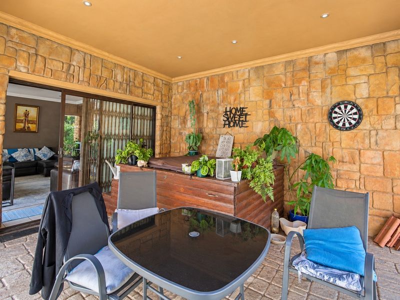 Covered patio area featuring stone-clad walls, recessed lighting, and paved flooring, providing a seamless transition to the interior living space through sliding glass doors.