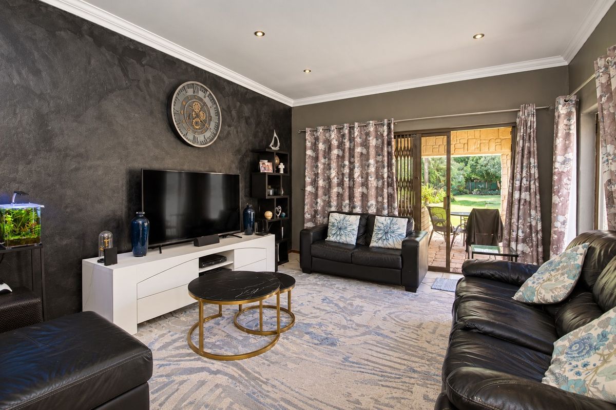 A well-maintained living room featuring a textured accent wall, recessed lighting, and direct access to an outdoor patio area through sliding glass doors.