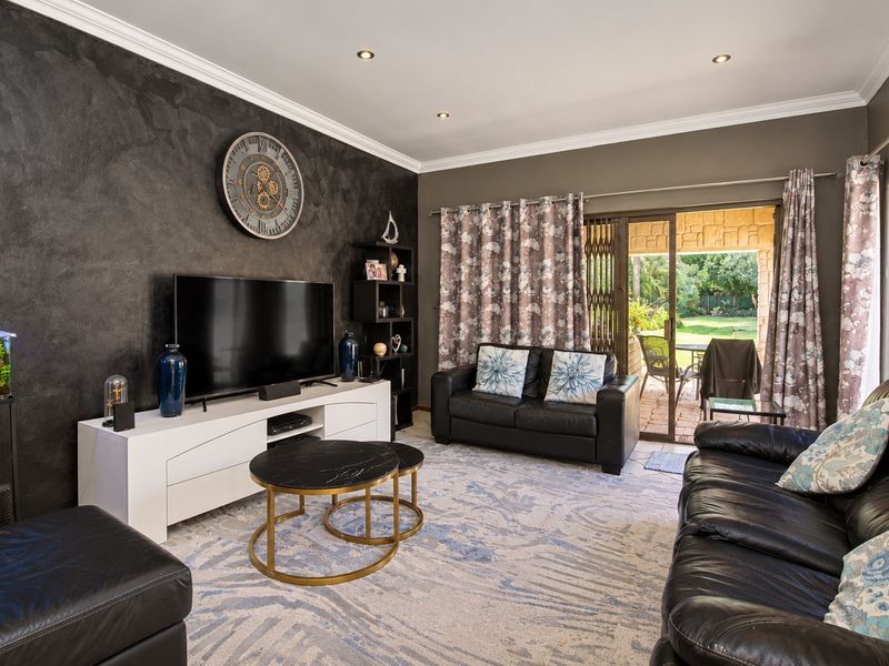 A well-maintained living room featuring a textured accent wall, recessed lighting, and direct access to an outdoor patio area through sliding glass doors.