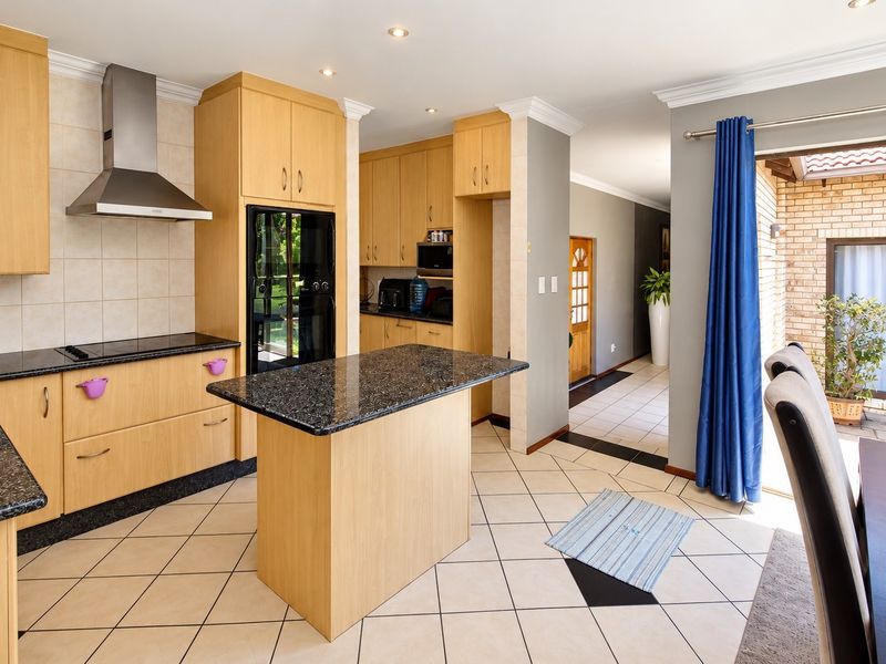 A functional kitchen featuring light wood cabinetry, granite countertops, a central island, and direct access to an outdoor patio area.