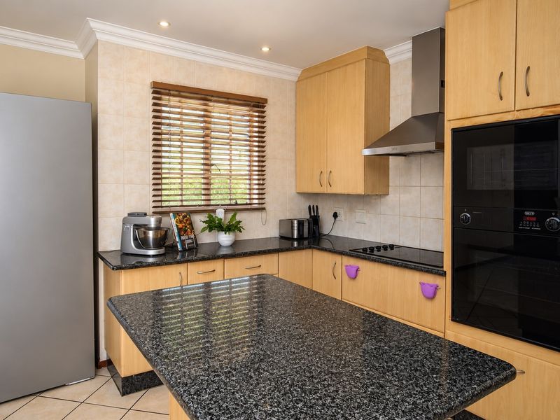 A functional kitchen featuring light wood cabinetry, dark granite countertops, built-in oven and microwave, and a tiled backsplash with recessed lighting.