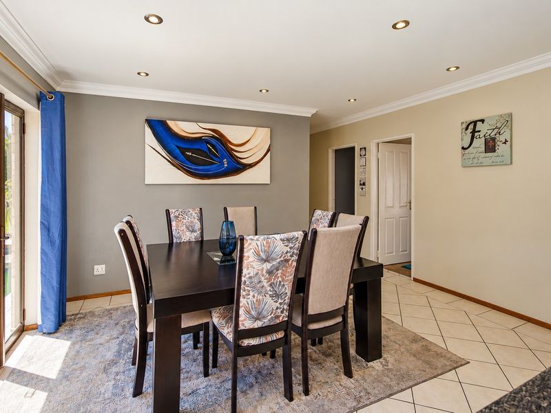 A bright dining area featuring ceramic floor tiles, recessed downlighting, and a large sliding glass door providing direct access to the outdoor pool area.